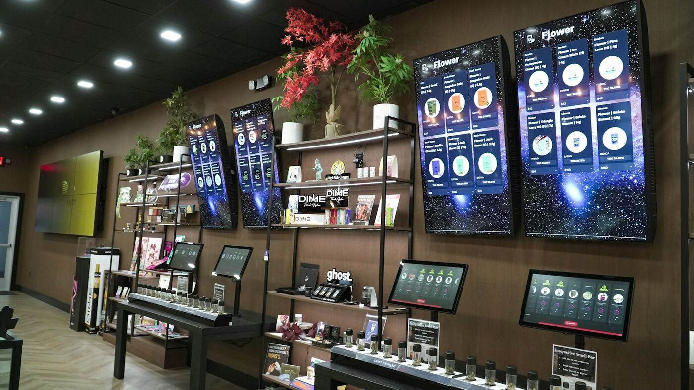 Retail wall of vertical digital menu boards and counter tablet kiosks showing crisp product content in a modern store
